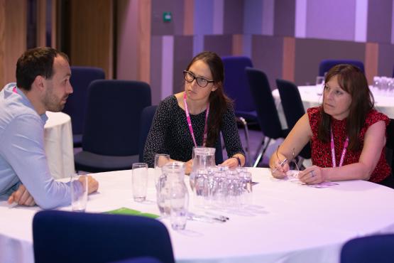 Three Healthwatch employees speak to each other at a conference.