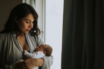 woman holding baby near a window